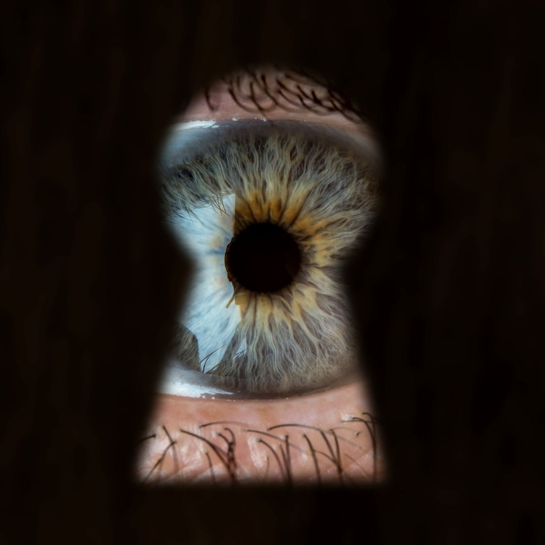 An eye peering through a keyhole