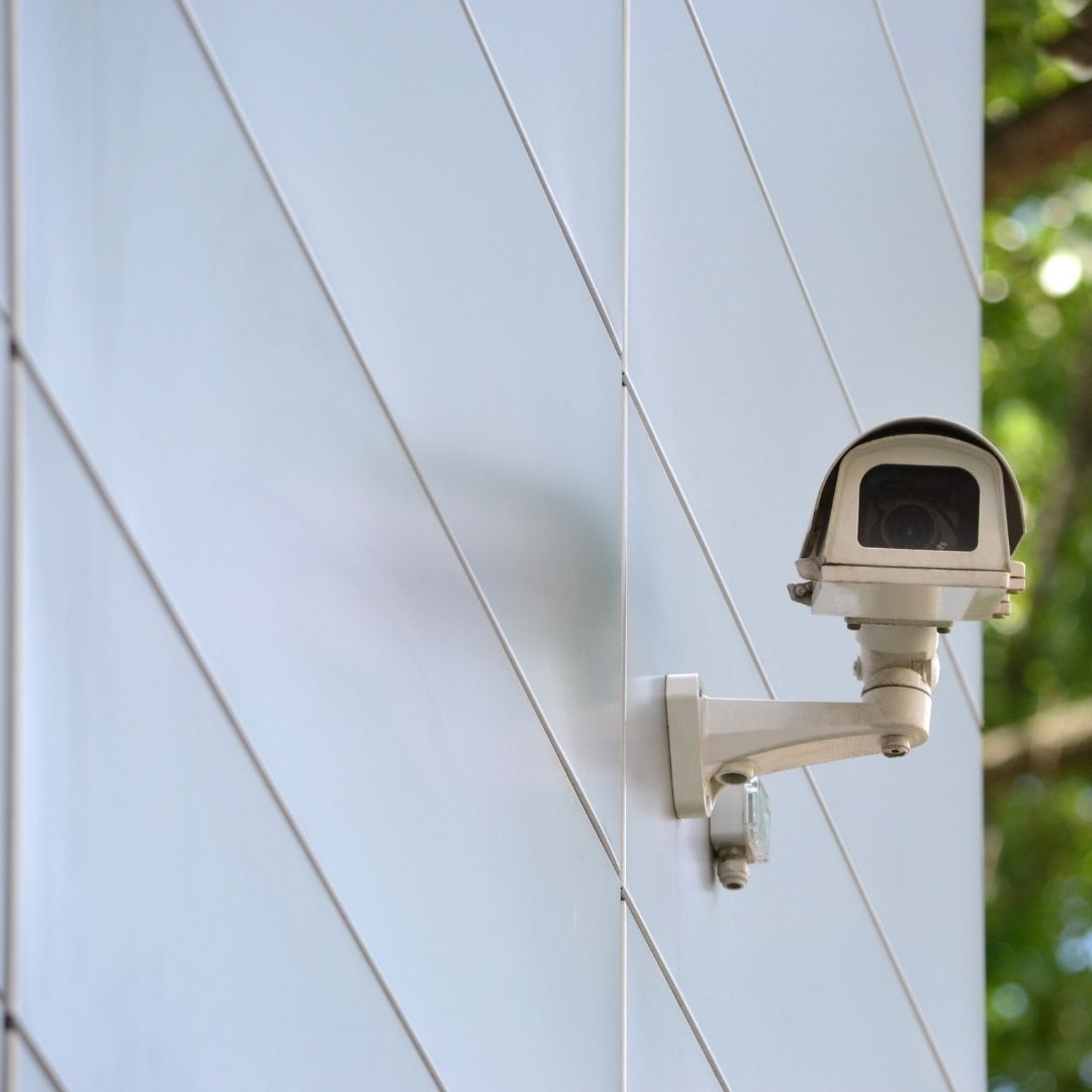 A surveillance camera on the side of a buildling