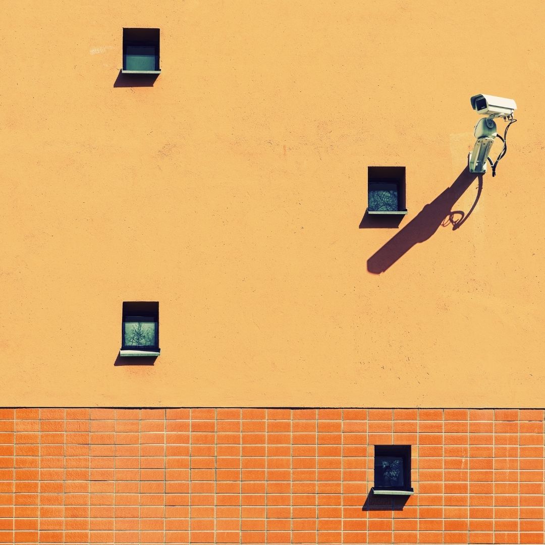 A surveillance camera on the side of an orange building